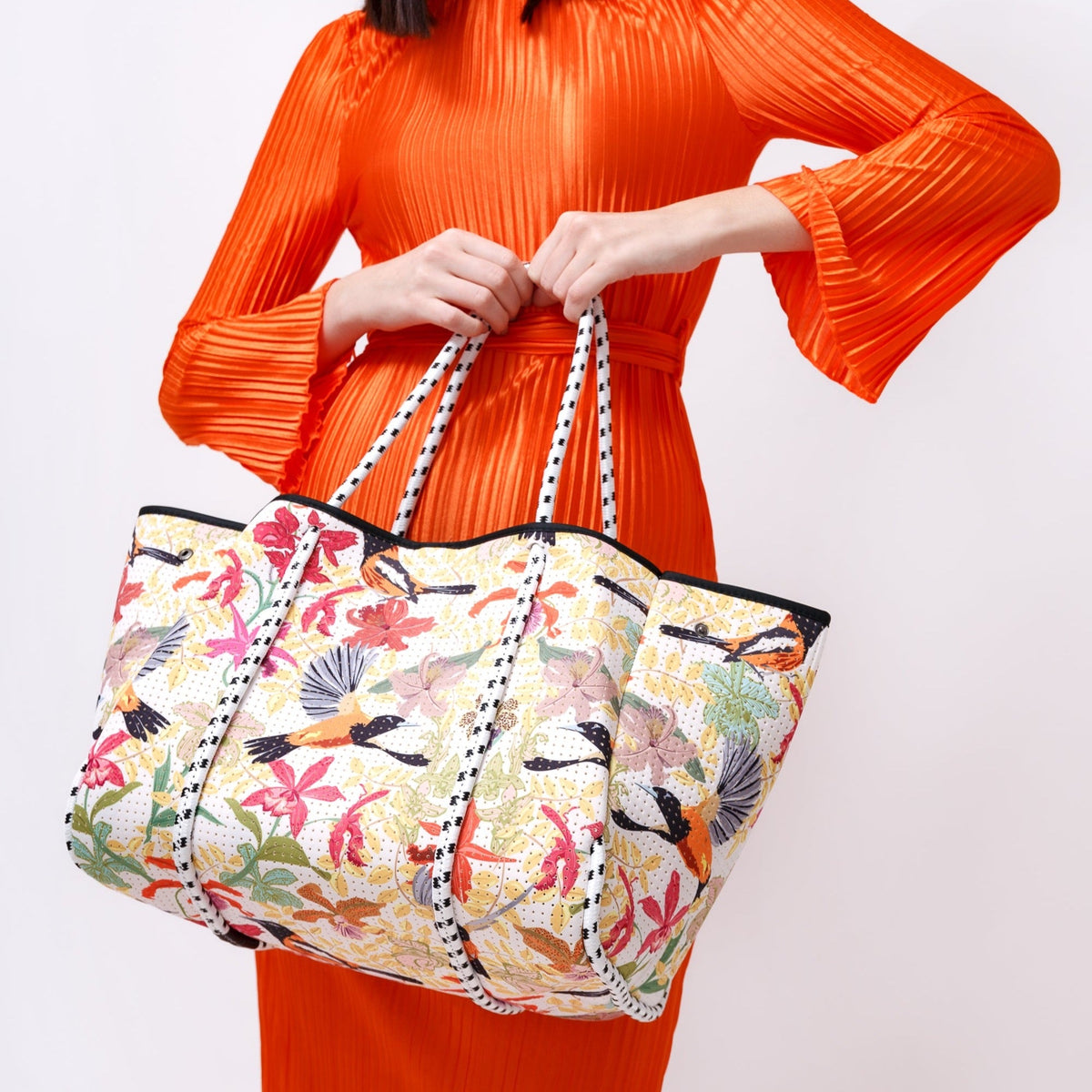 Floral tote bag with striped handles and front pocket with black trim