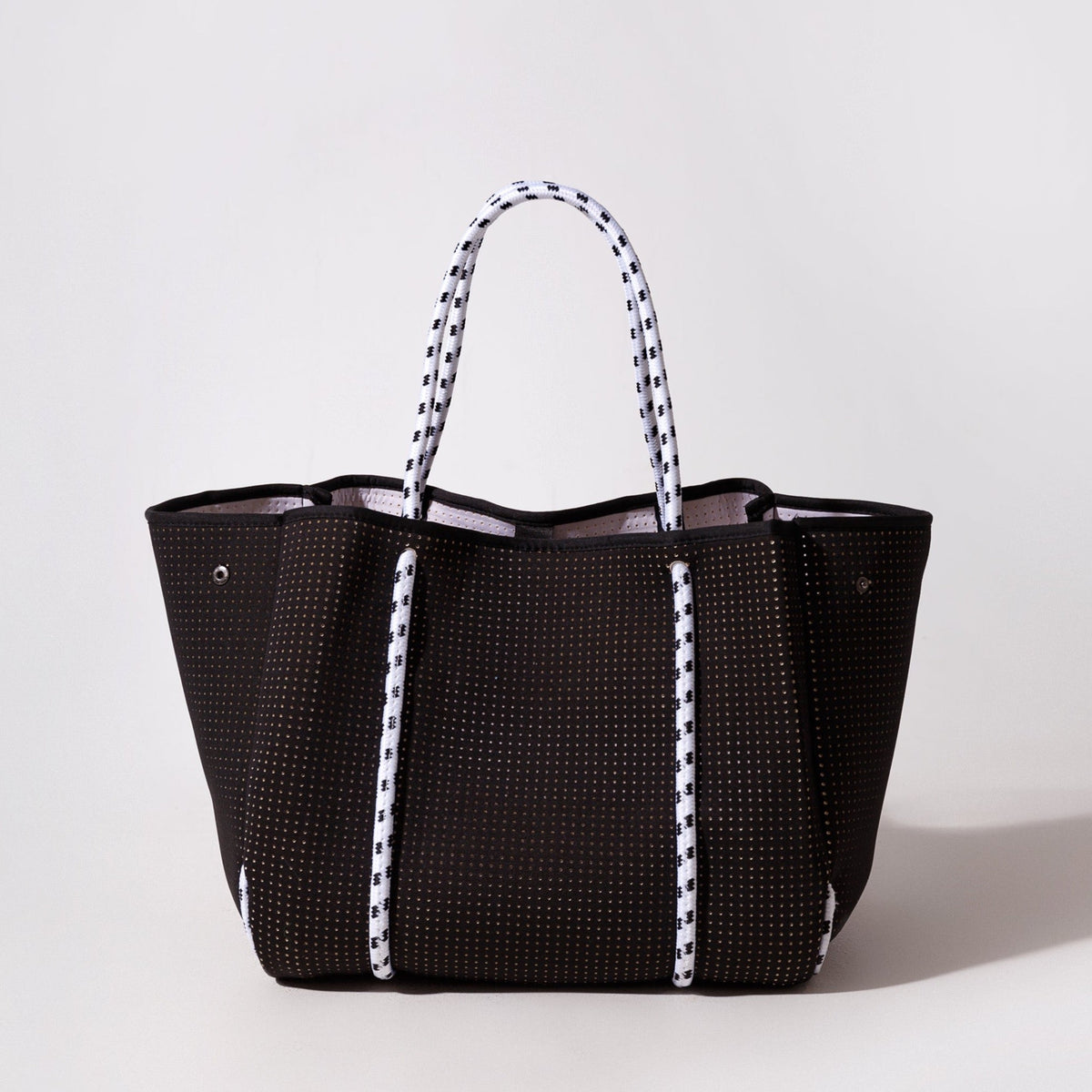 Black perforated tote bag with striped handles and open top.