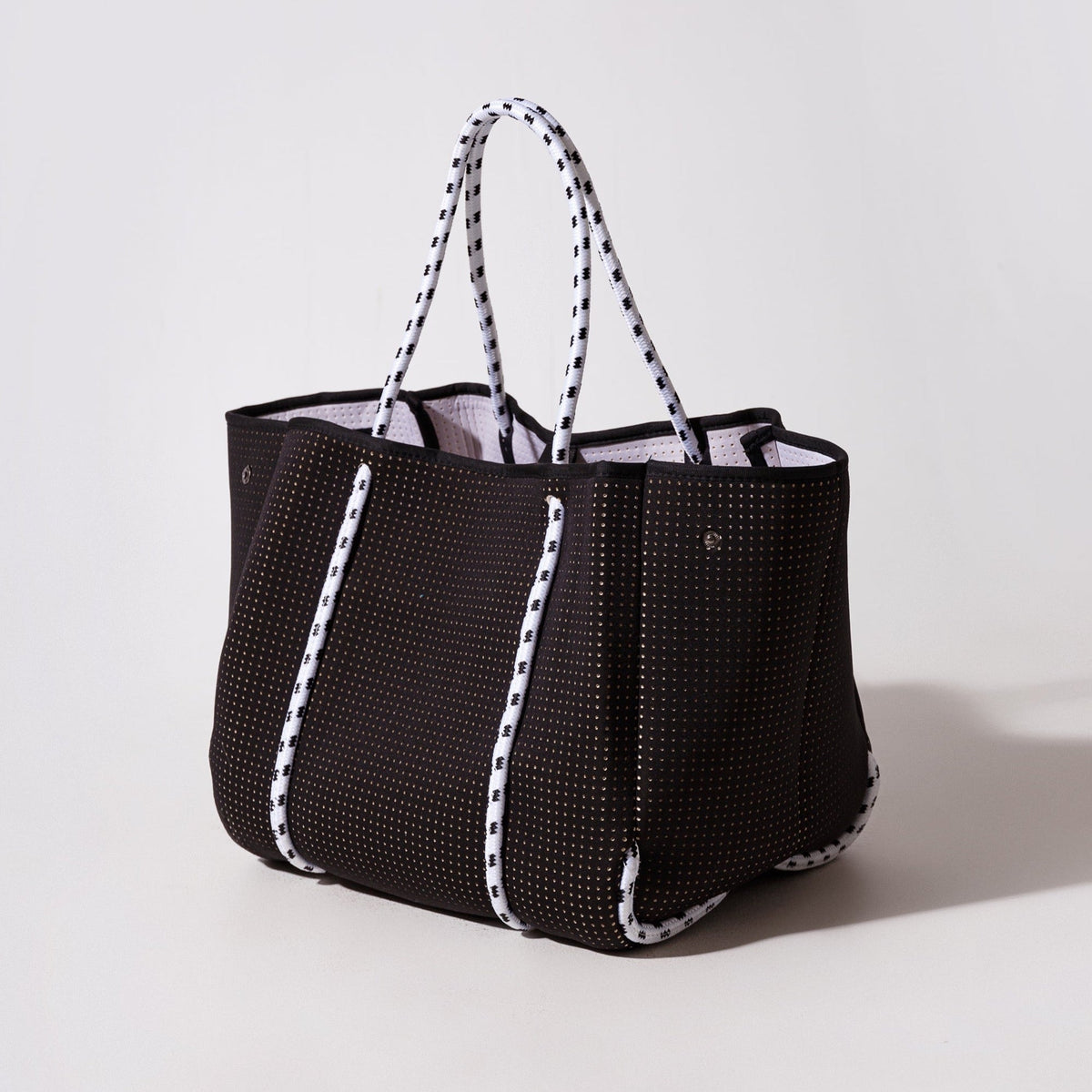 Black perforated tote bag with striped top handles and structured sides.