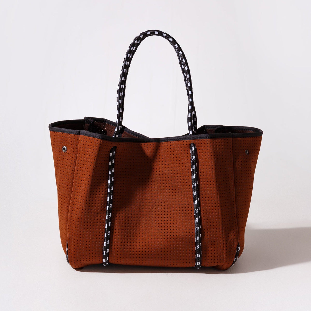 Rust-brown perforated tote with black lining, open top, patterned black handles