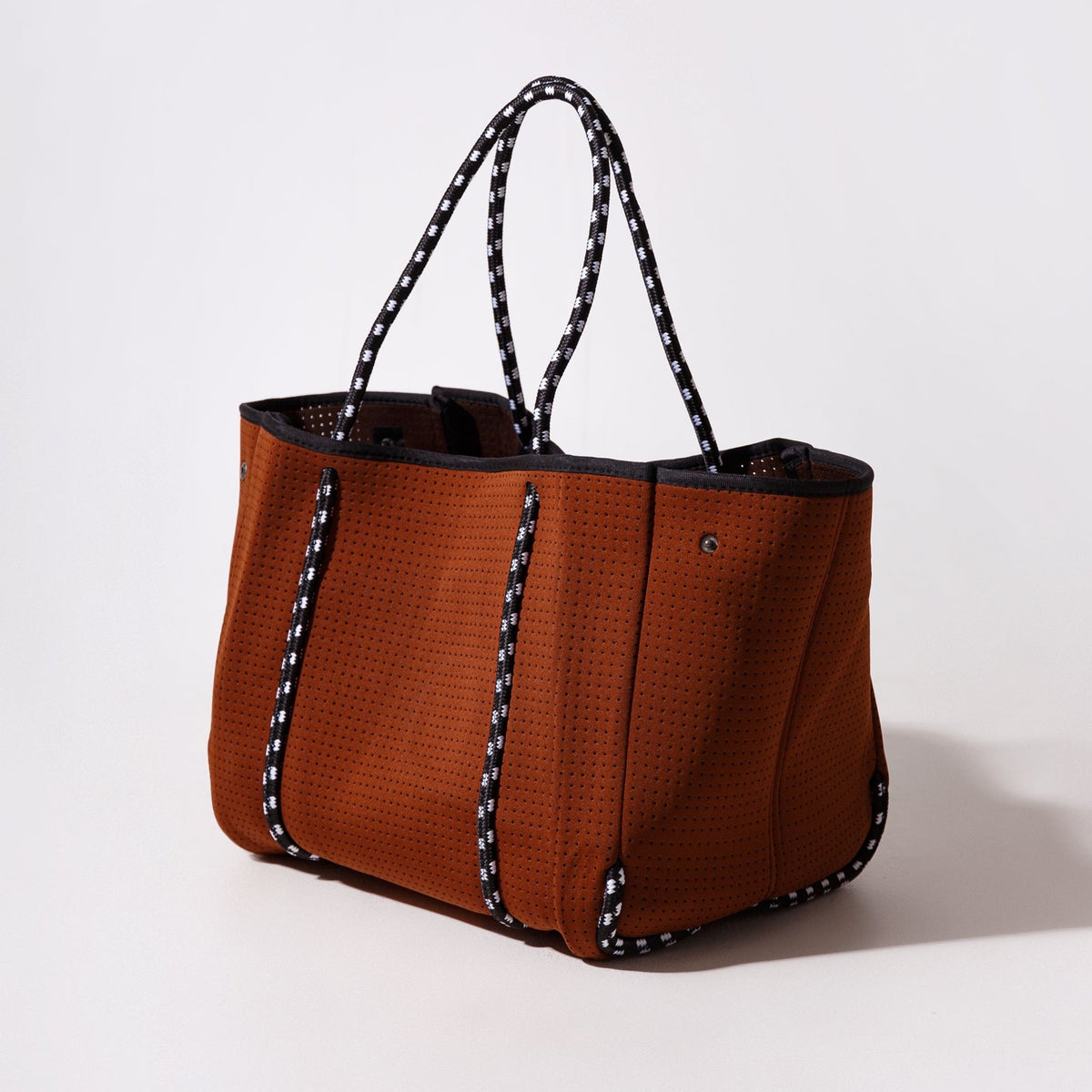 Rust-brown perforated tote bag with dual handles and black trim