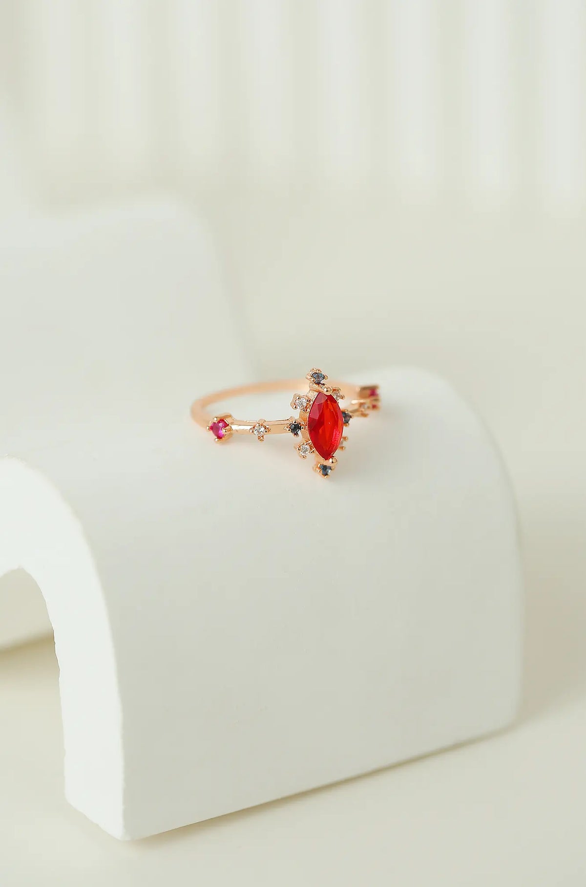 Marquise-cut ring with a red center stone and small colored accents, shown from the front