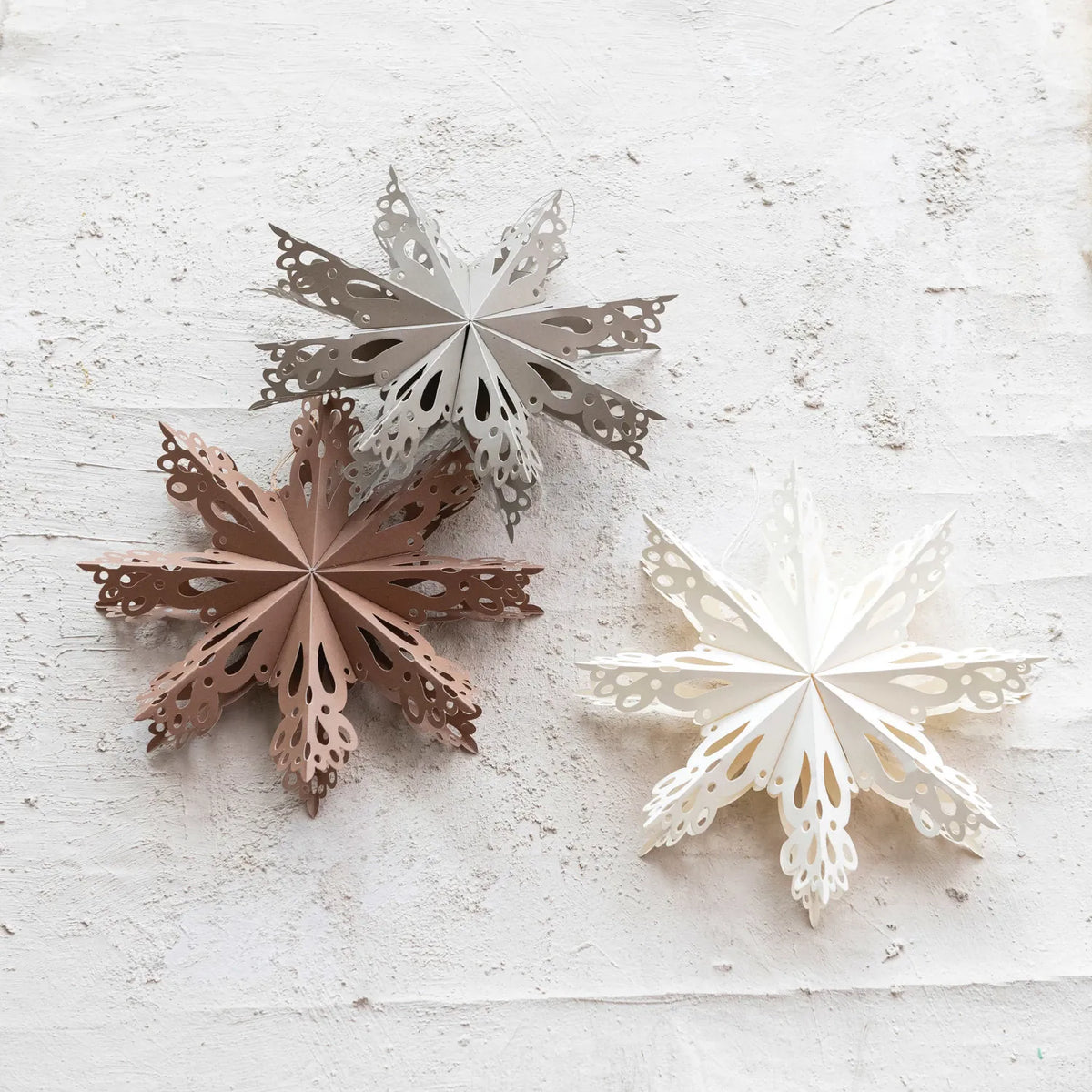 Recycled paper snowflake ornaments in dark brown and white, two hanging pieces