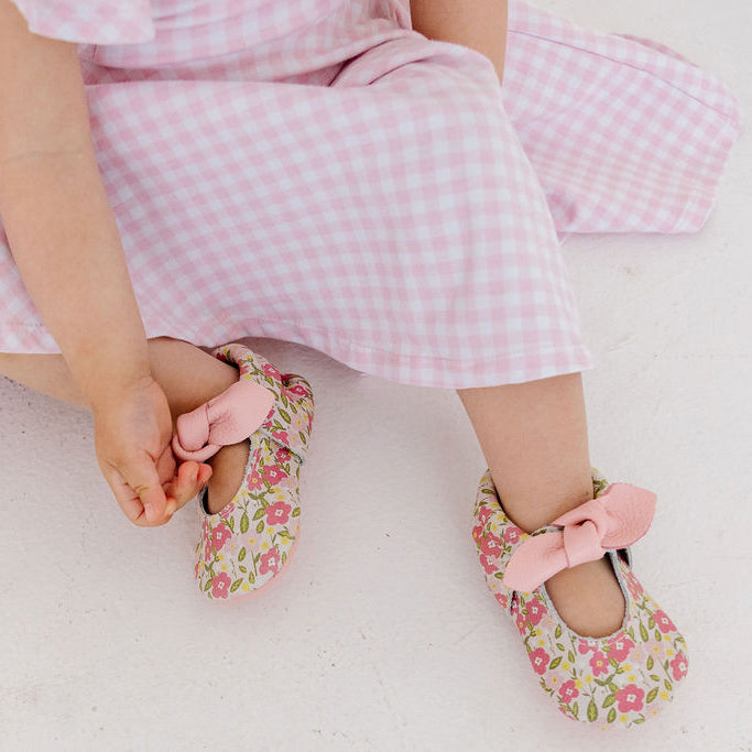 Baby floral shoes with knotted pink bows, worn with a pink gingham dress