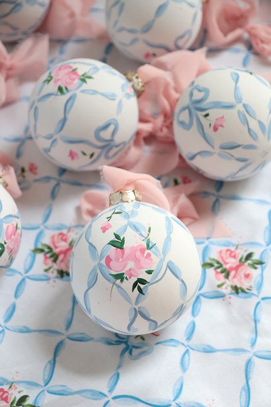 Hand-painted white ornament with blue ribbon trellis and pink roses