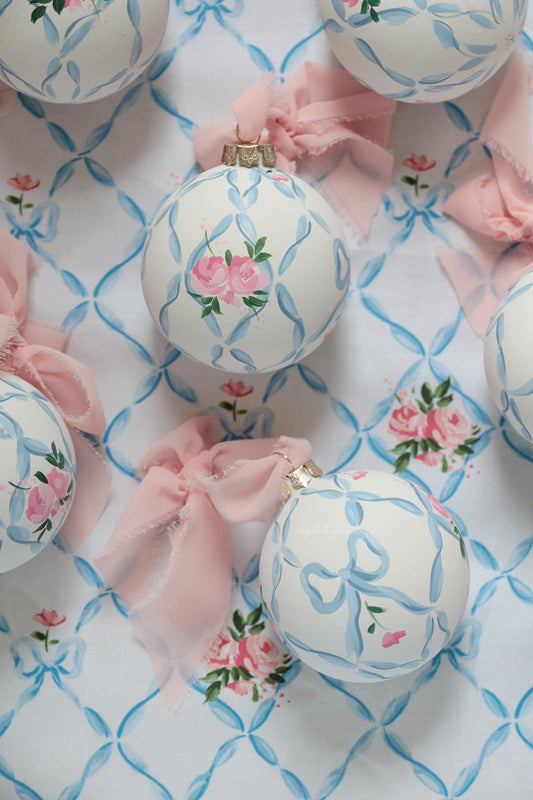 Round floral ornament with blue ribbon trellis, pink roses, and gold-tone cap