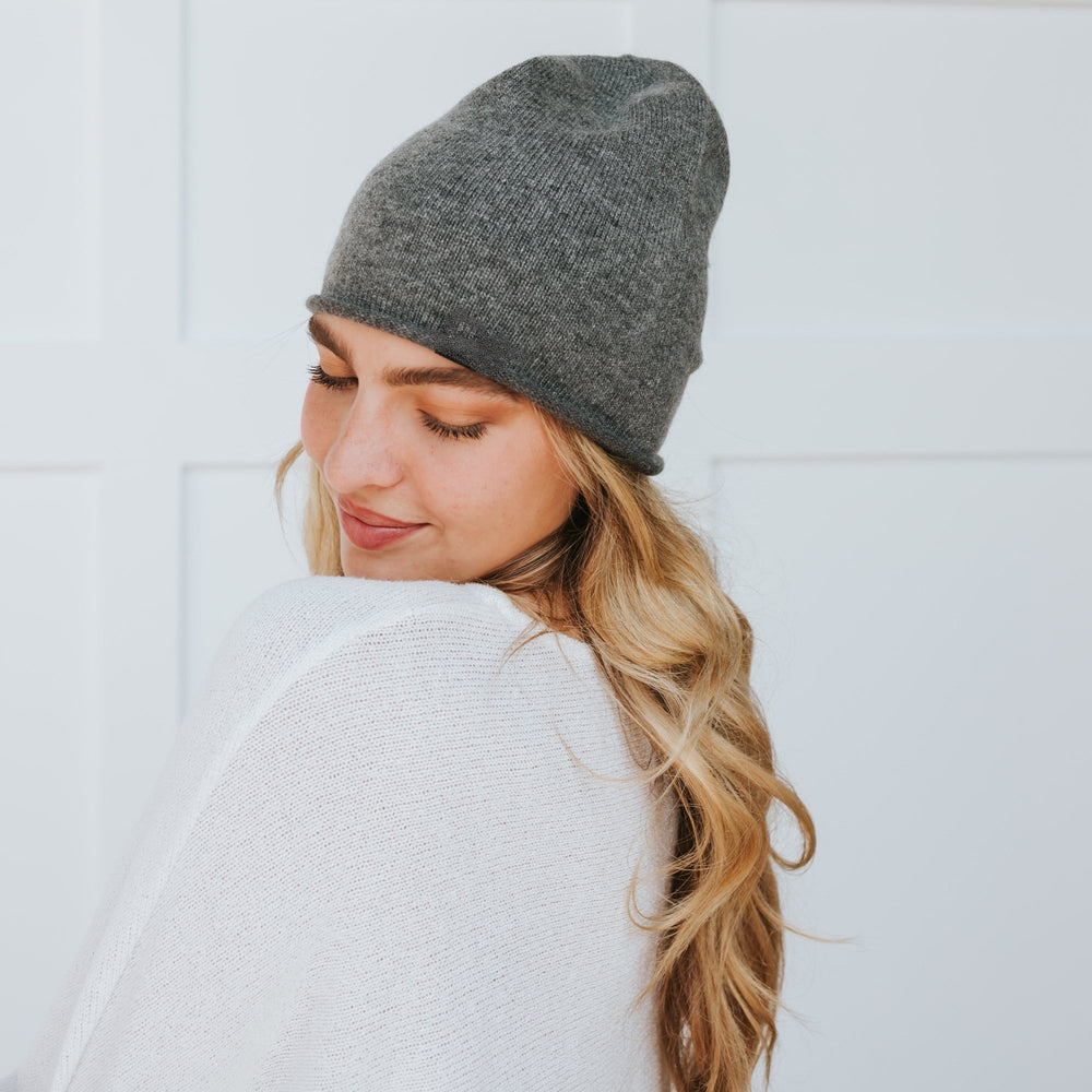 Charcoal gray cashmere beanie with a rolled edge, shown from the side