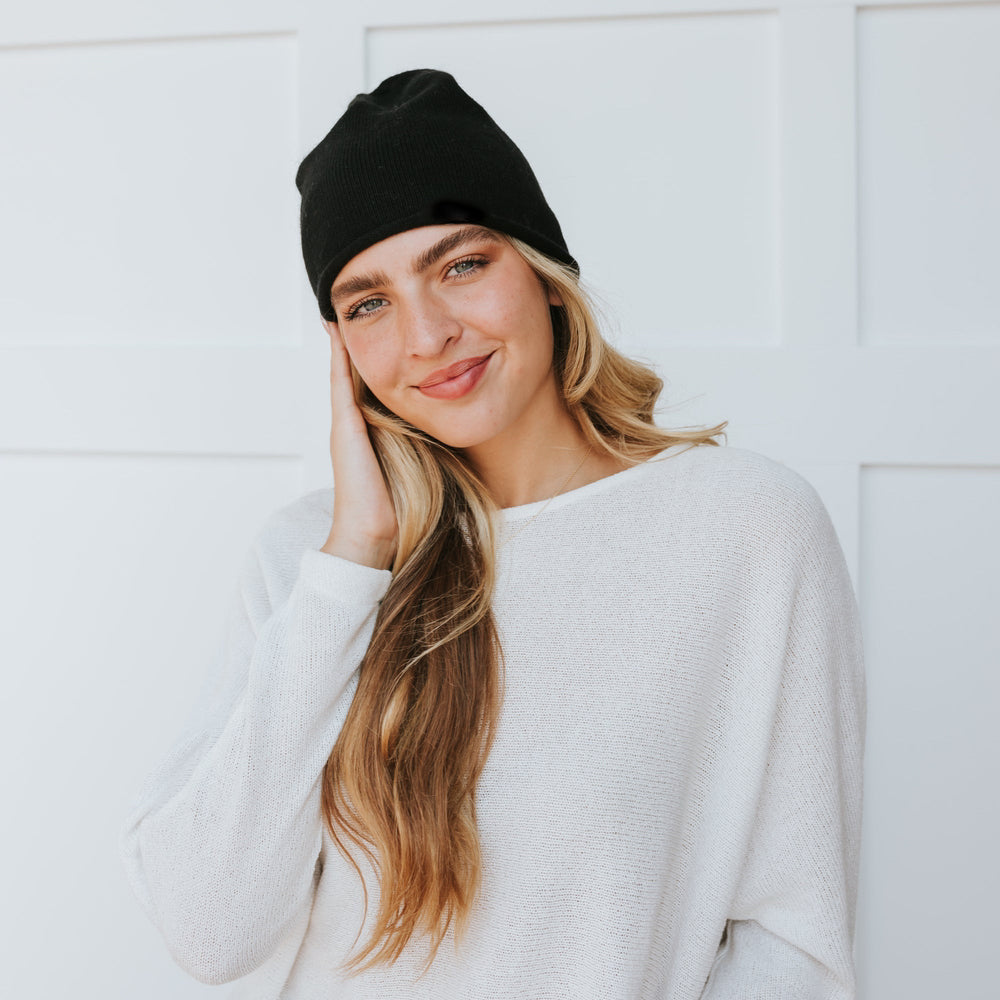 Black rolled-edge cashmere beanie worn with a white sweater