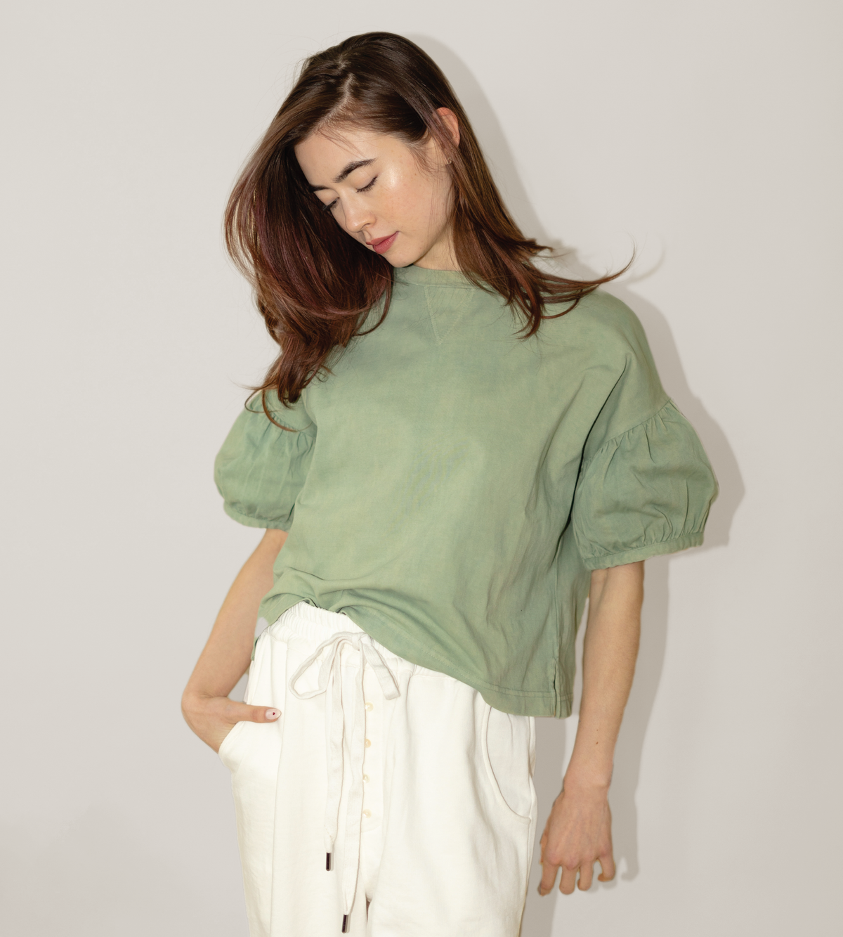 Sage green tee with a cropped fit and gathered puff sleeves, worn with white pants
