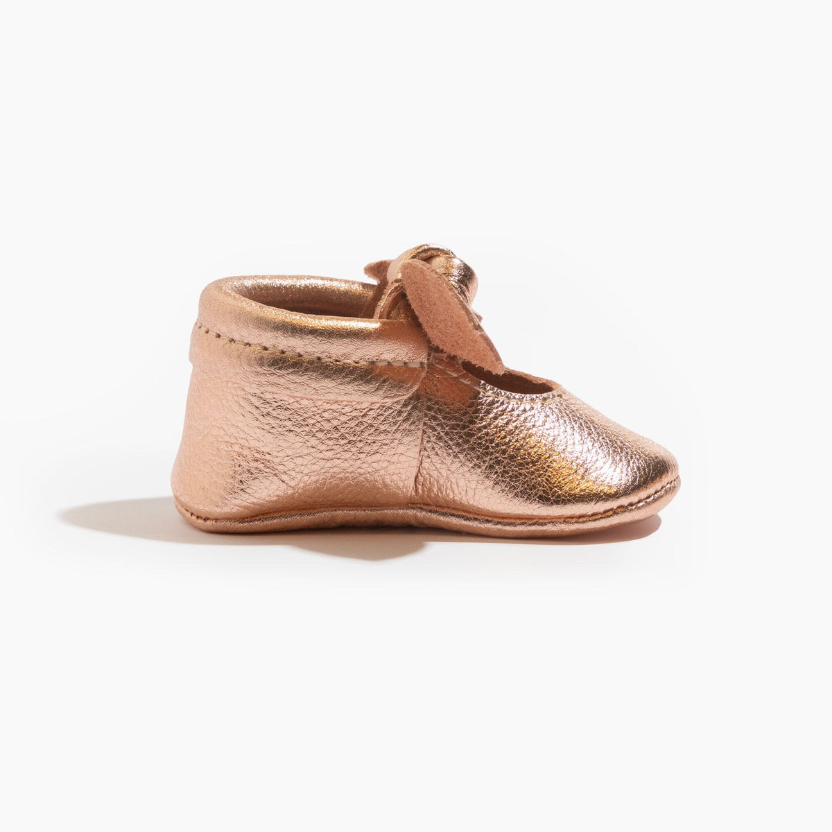 Rose gold baby shoe with knotted bow, front side view, closed toe