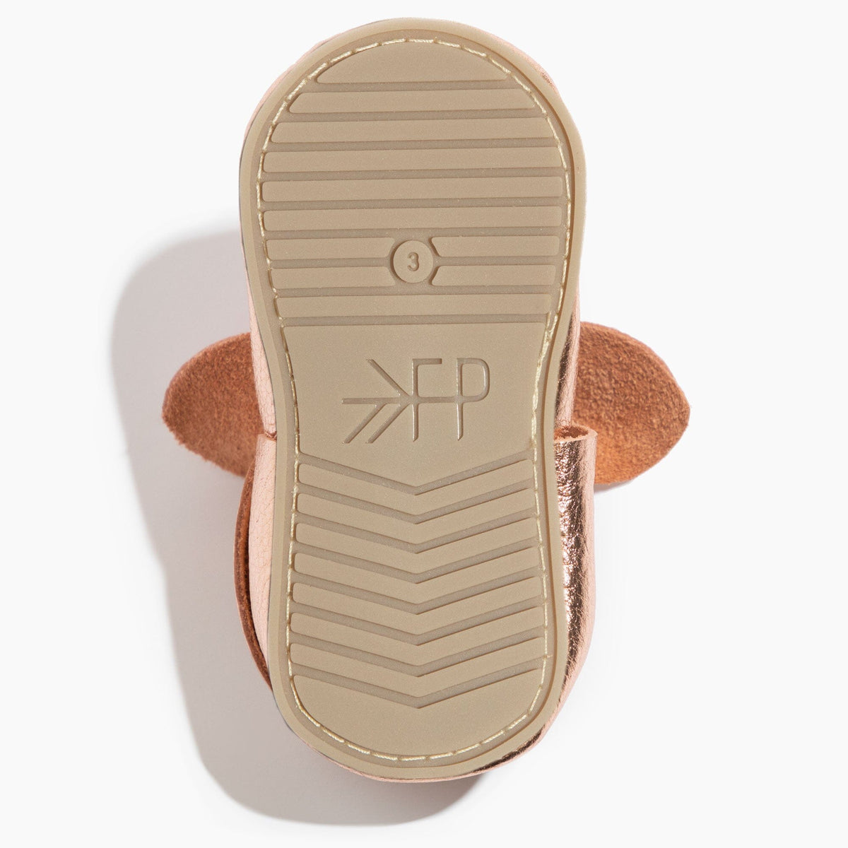 Rose gold baby shoe outsole view with traction tread and logo markings