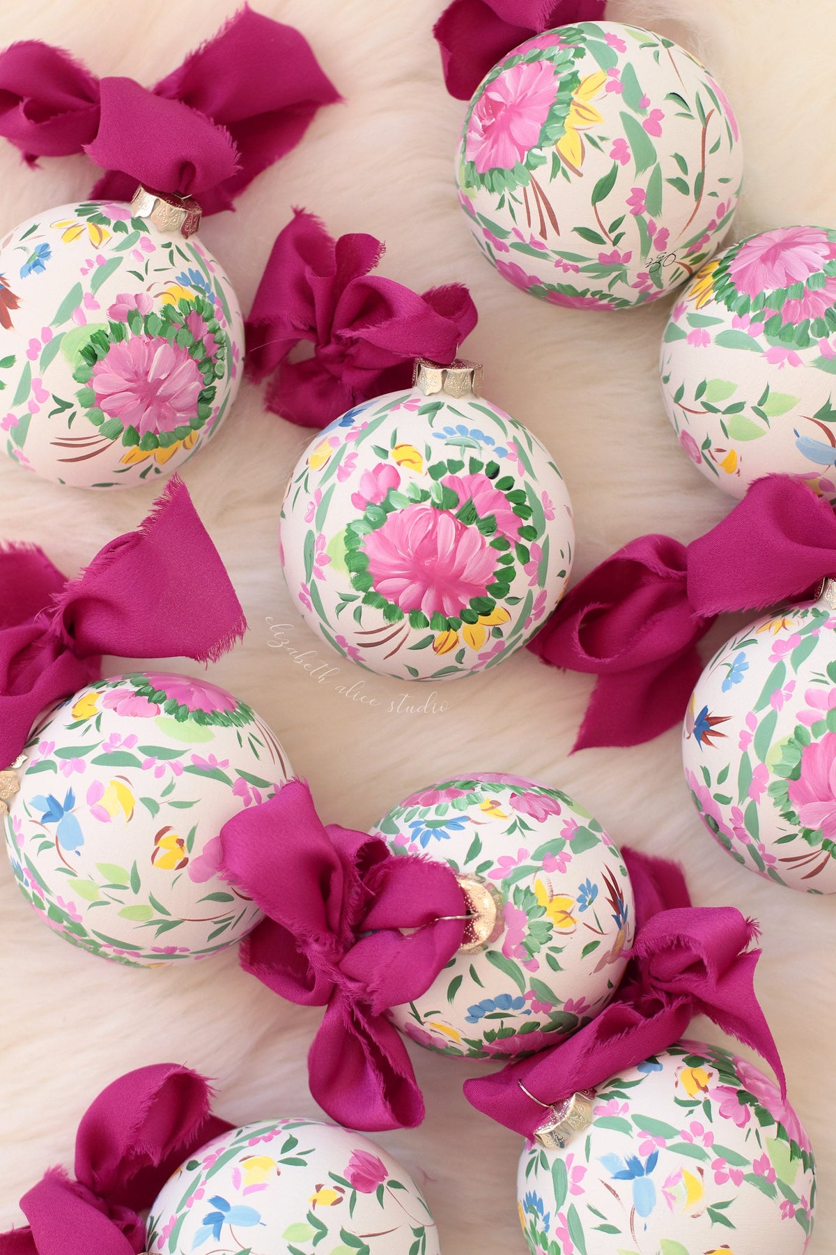Hand-painted floral ornaments with pink medallions and magenta fabric bows
