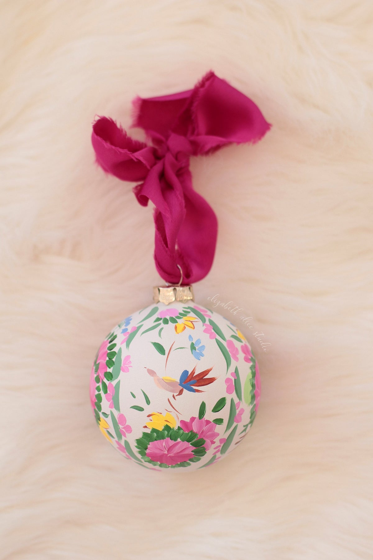 Hand-painted ornament with a small blue bird, flowers and magenta bow