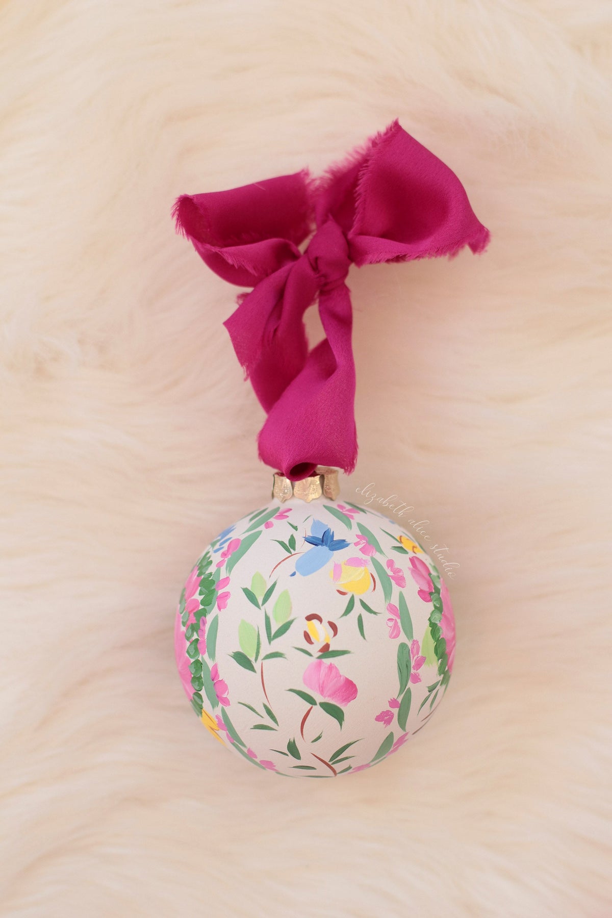 Hand-painted ornament with scattered flowers and leaves, tied with a magenta bow