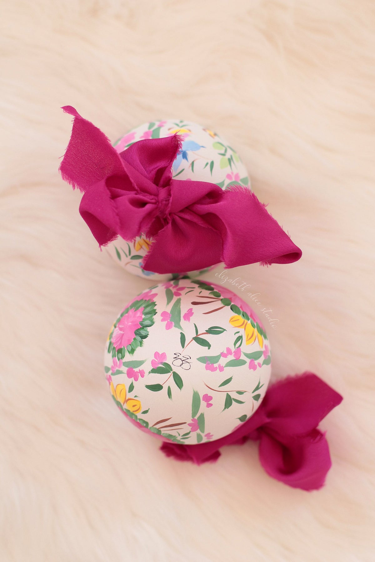 Hand-painted ornament with a floral and bird pattern and magenta fabric bow