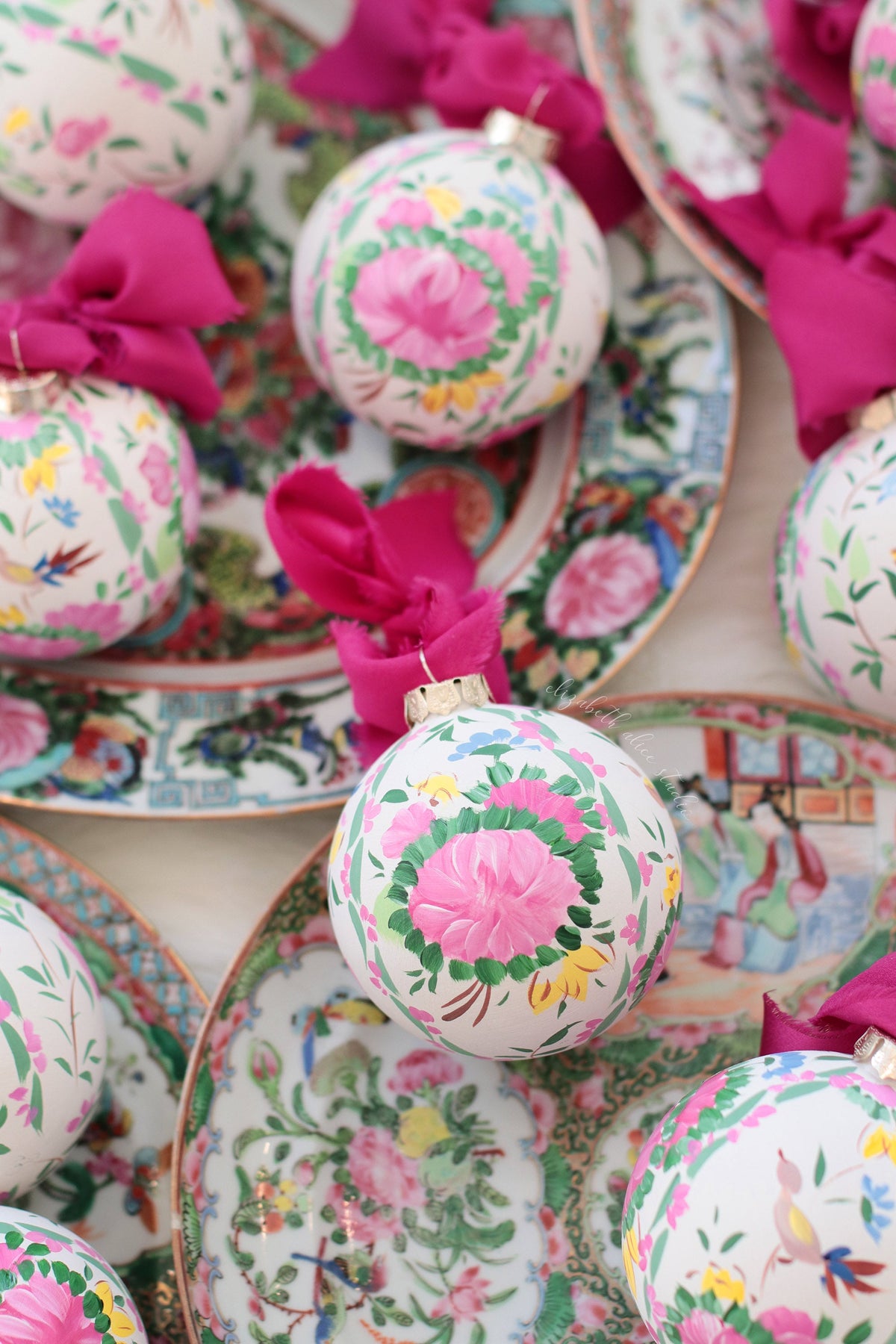 Close view of a hand-painted rose medallion ornament with a magenta bow