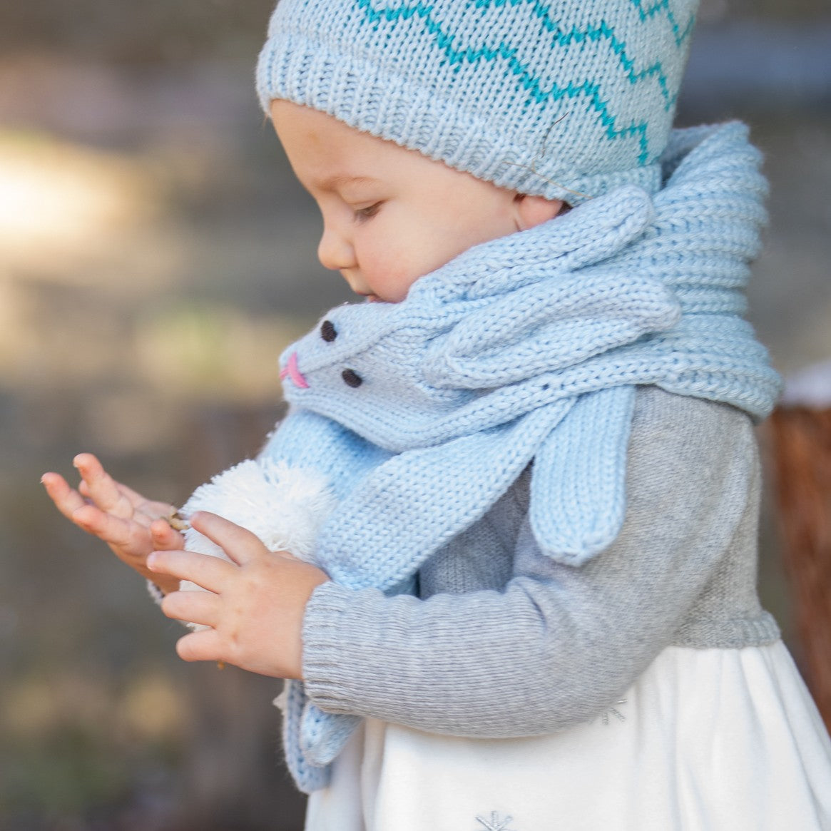 Pale blue rabbit scarf shown close up, with a face, floppy ears and pom-pom tail