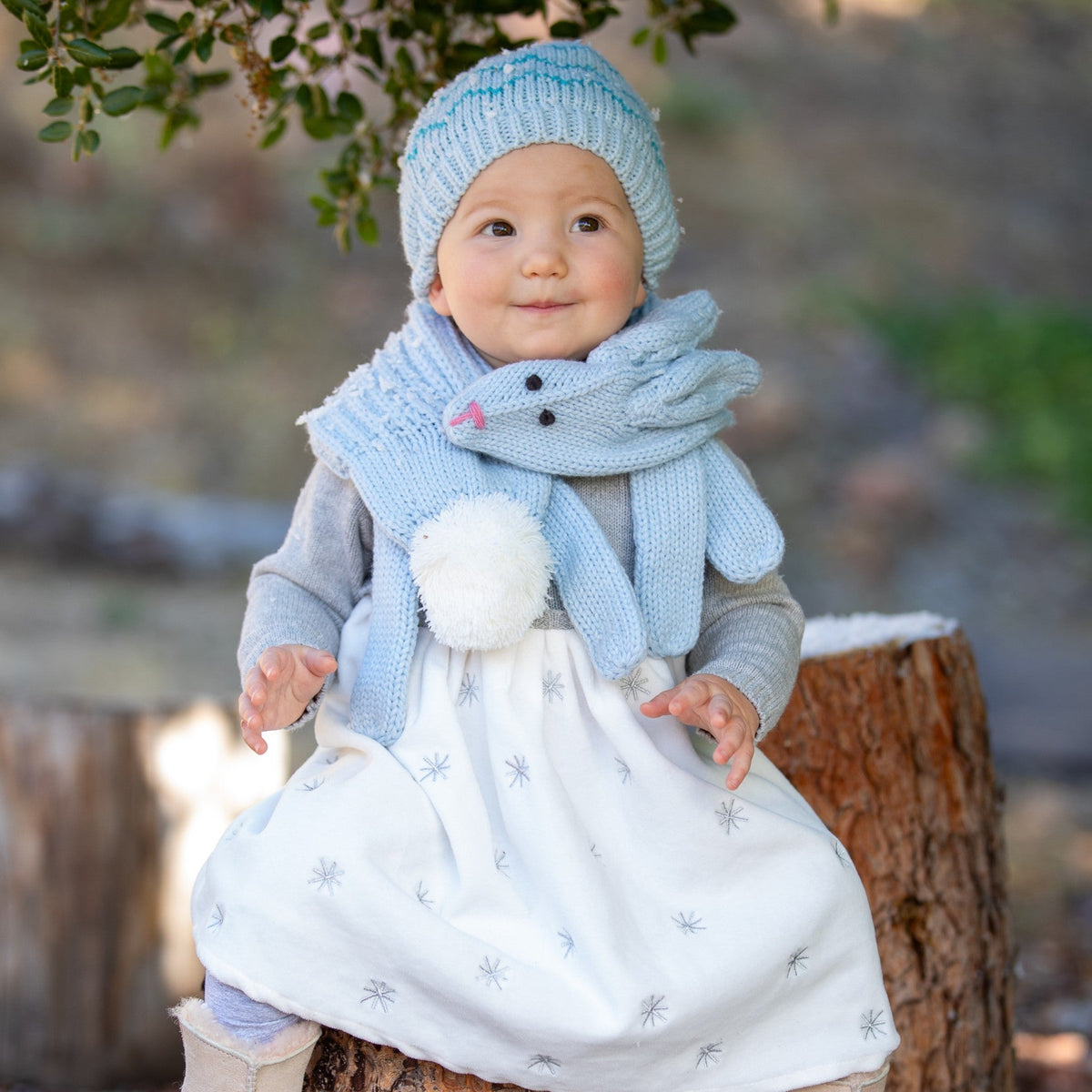 Pale blue rabbit scarf worn around a child's neck, with dangling ends and a pom-pom tail