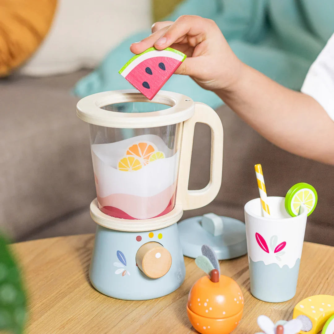 Hands add watermelon slice to toy blender jug with fruit cup and accessories