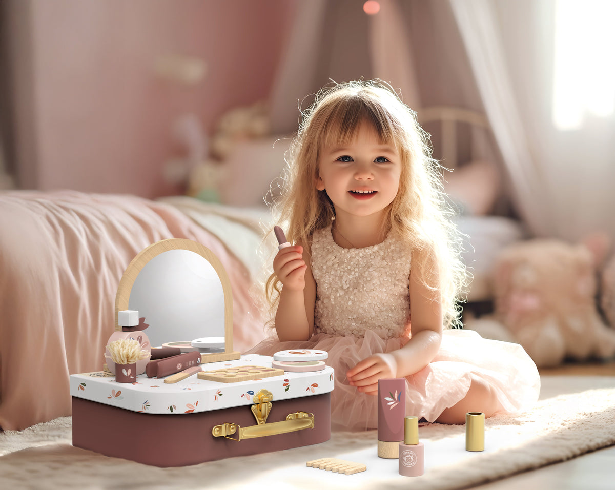Child playing with floral makeup vanity suitcase and toy cosmetics on bed