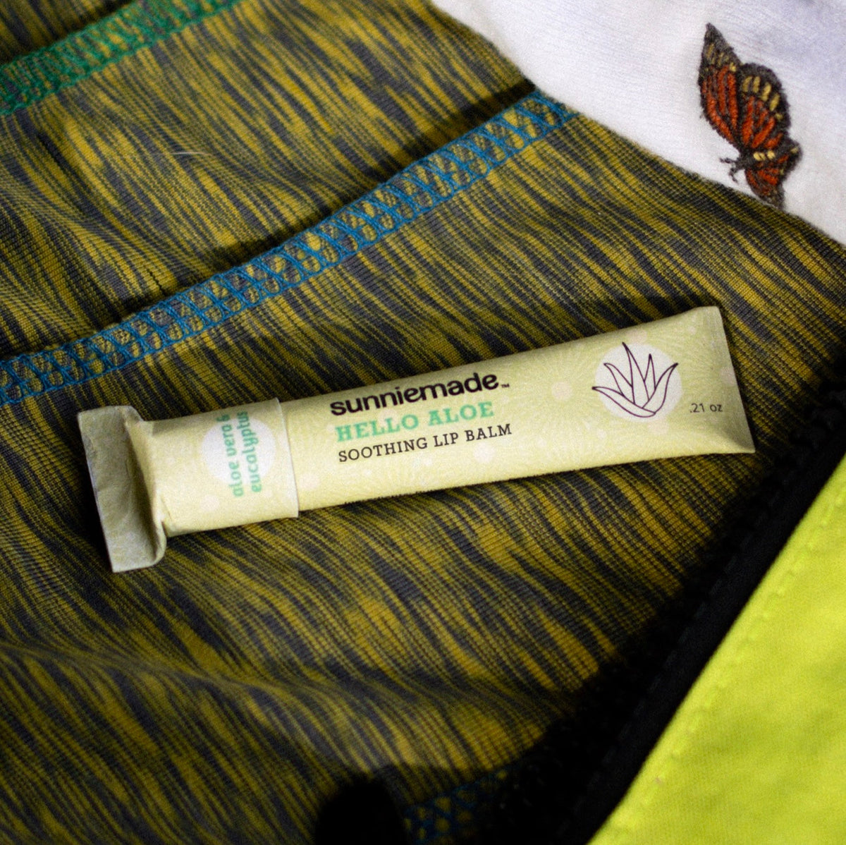 sunniemade Hello Aloe soothing lip balm tube with cap on dark fabric