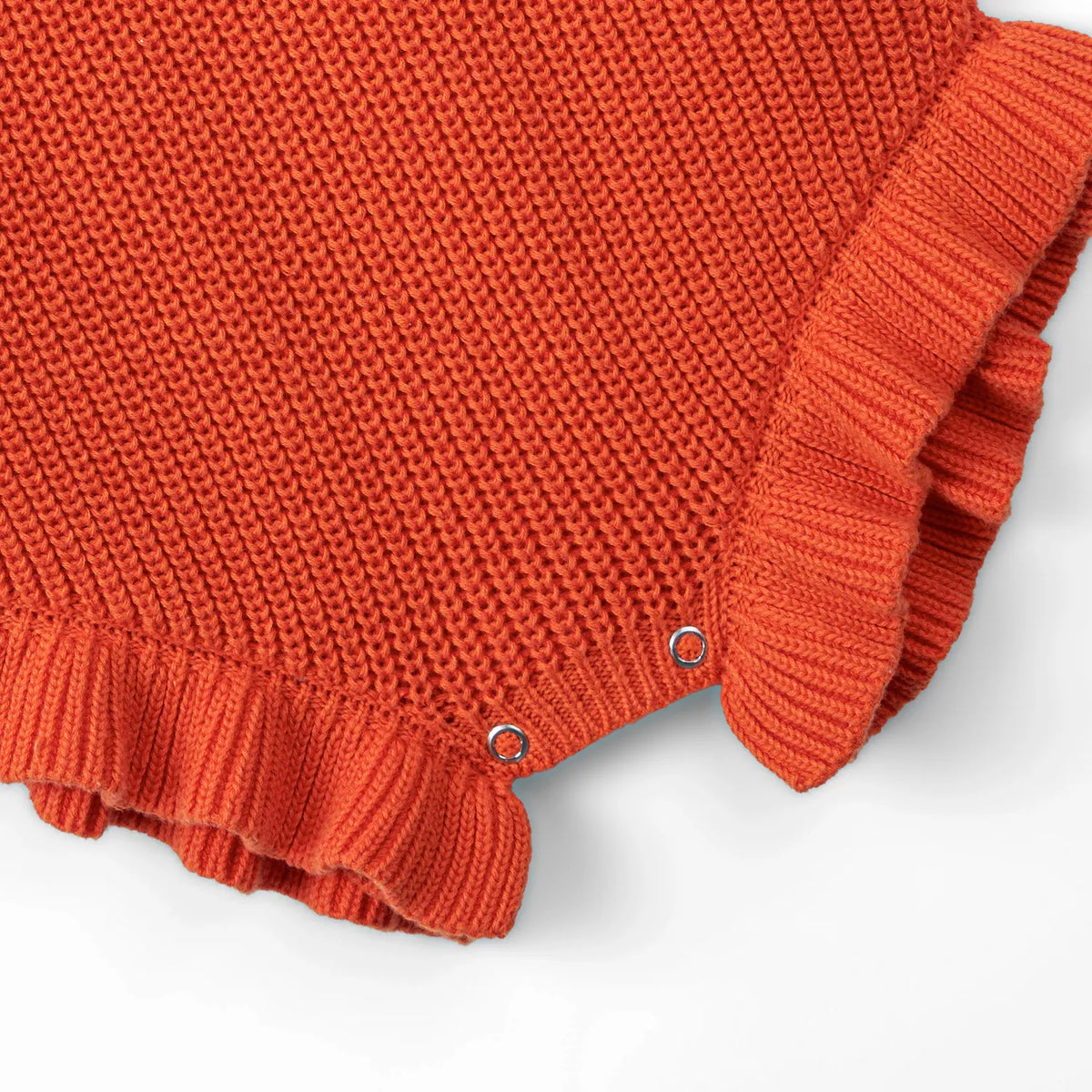 Orange-rust chunky knit romper side view with snap buttons and ruffled cuff trim