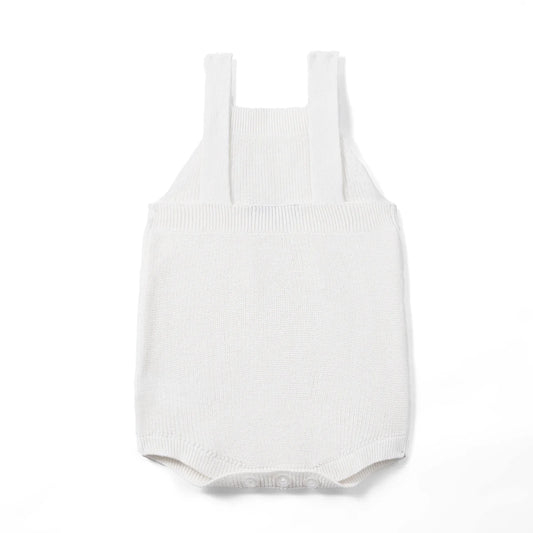 White knit baby romper with button shoulder straps and ribbed leg openings.