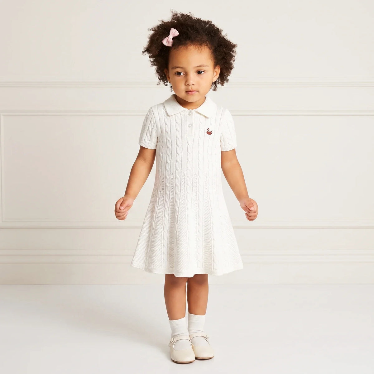 White cable-knit polo dress with short sleeves, button placket, and small chest emblem.
