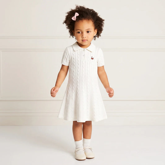 White cable-knit polo dress with short sleeves, button placket, and small chest emblem.