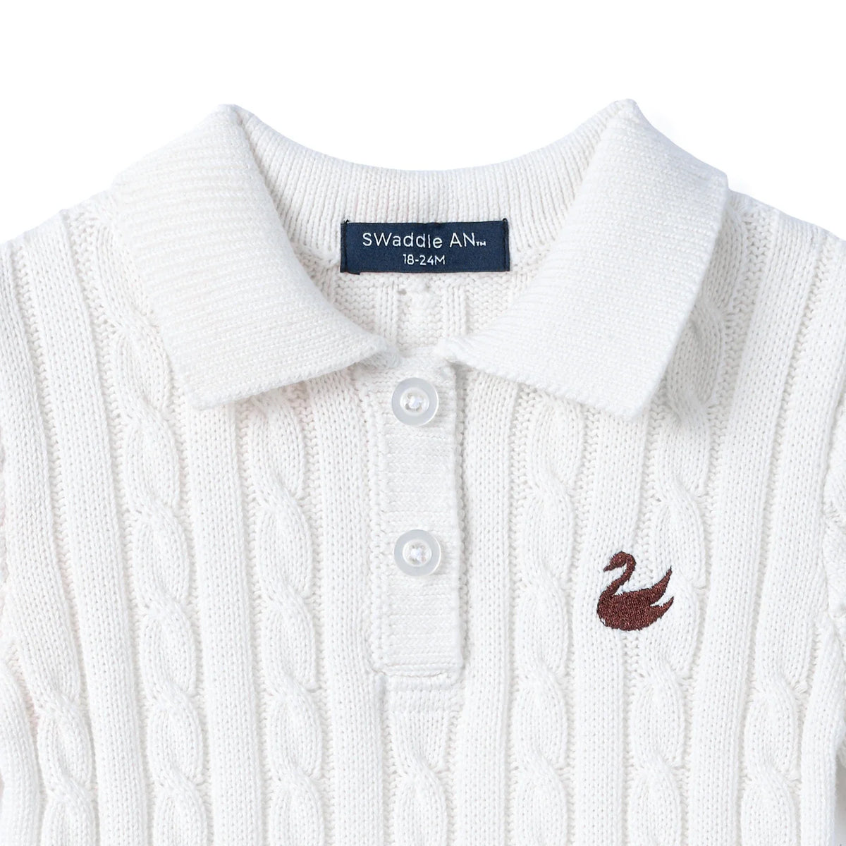 White cable-knit polo dress close-up: collared neckline, button placket, chest emblem.