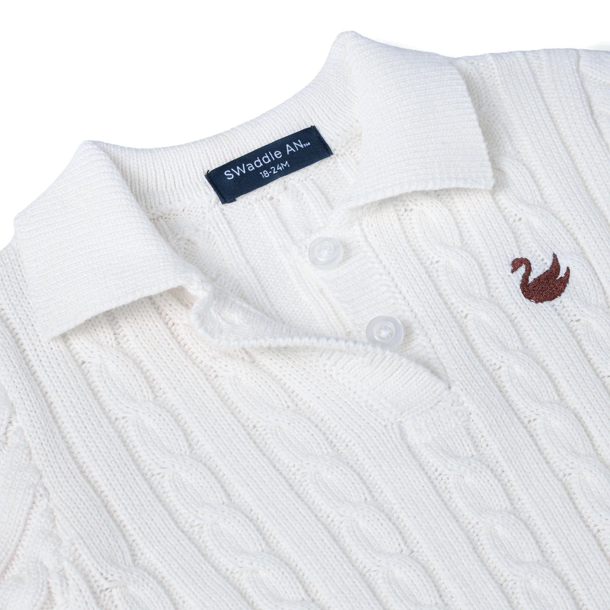 White cable-knit polo dress close-up: knit collar, button placket, small chest emblem.