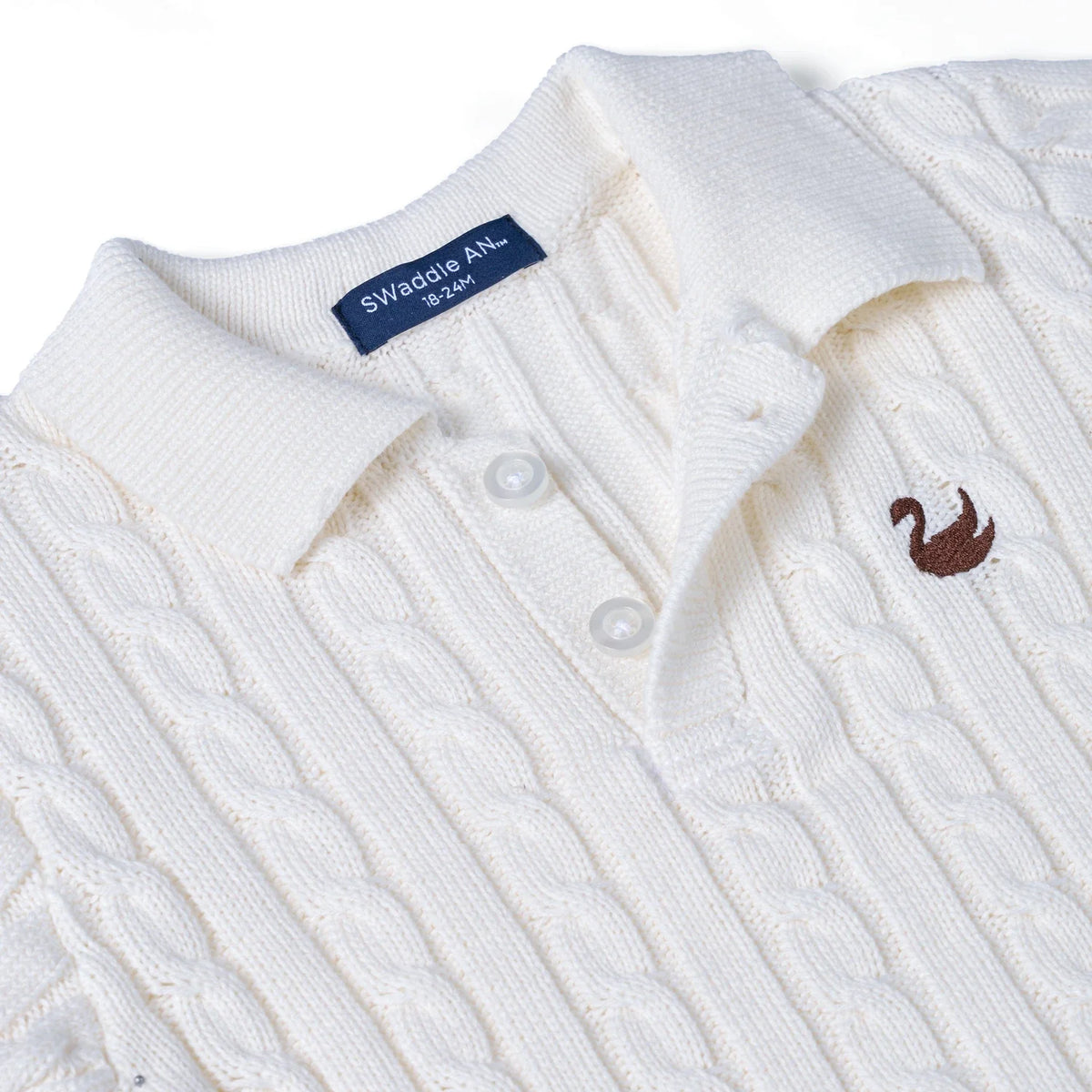 White cable-knit polo sweater close-up of knit texture and two-button placket