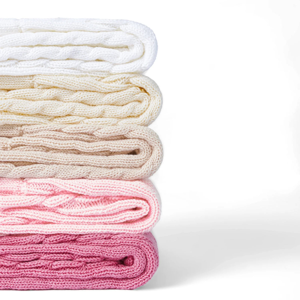Folded cable-knit shorts in pale pink and cream tones, stacked for display