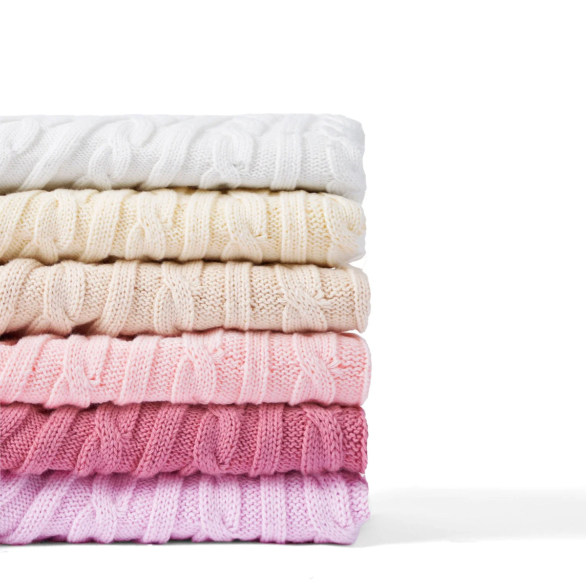 Stack of folded cable-knit skirts in white, cream, and pink