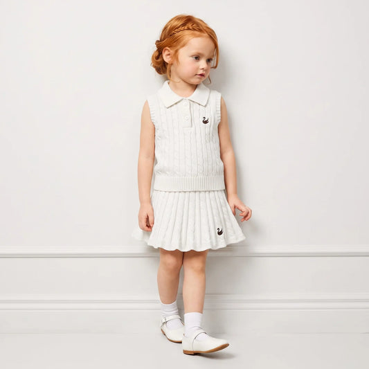 White cable-knit sleeveless polo shirt on a child, ribbed collar and buttons