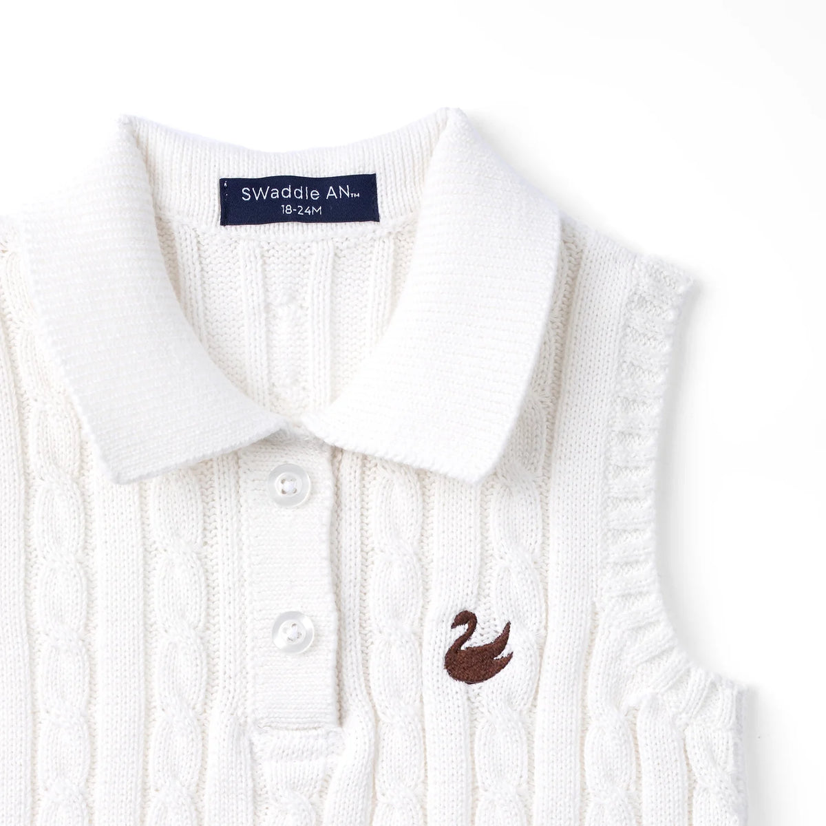 White cable-knit sleeveless polo shirt closeup, bird logo and button placket