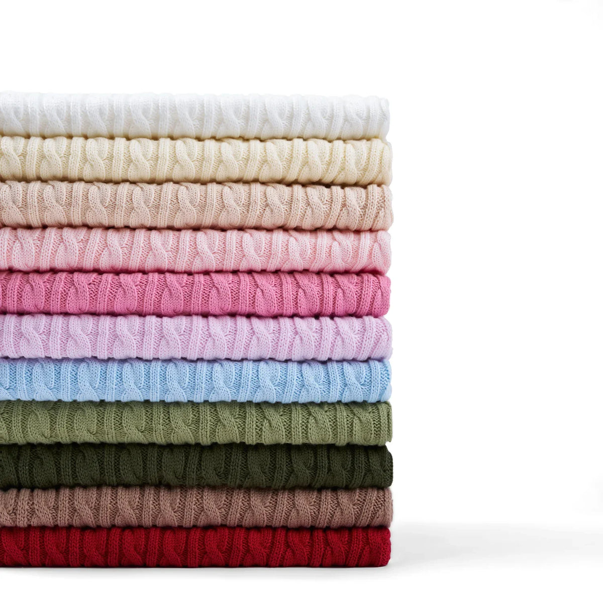 Stack of cable knit baby sweaters in white, pink, blue, green and red