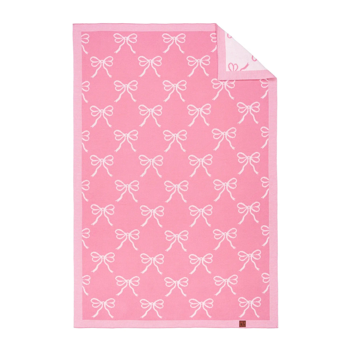 Pink baby blanket with white bow jacquard pattern, folded corner detail.