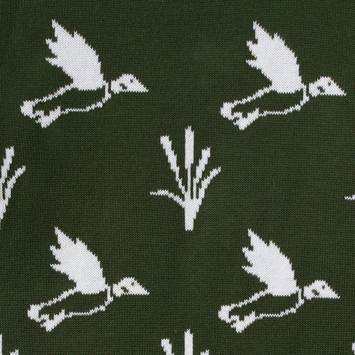 Close-up dark green knit sweater fabric with white duck and plant pattern
