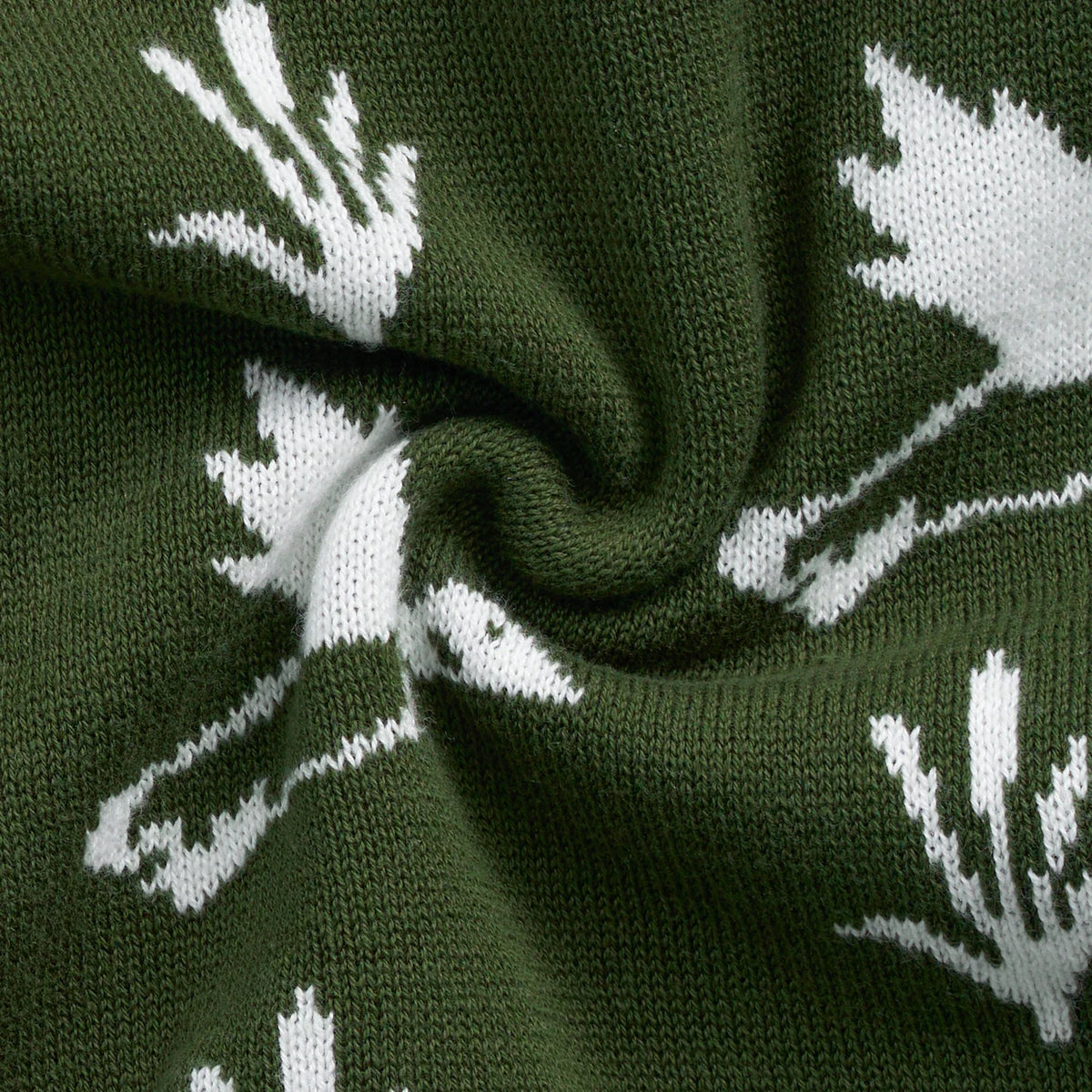Knit sweater fabric close-up with dark green base and white duck and plant pattern