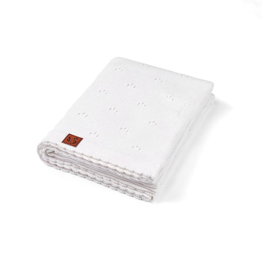 White pointelle knit baby blanket, folded with stitched edge and small logo patch
