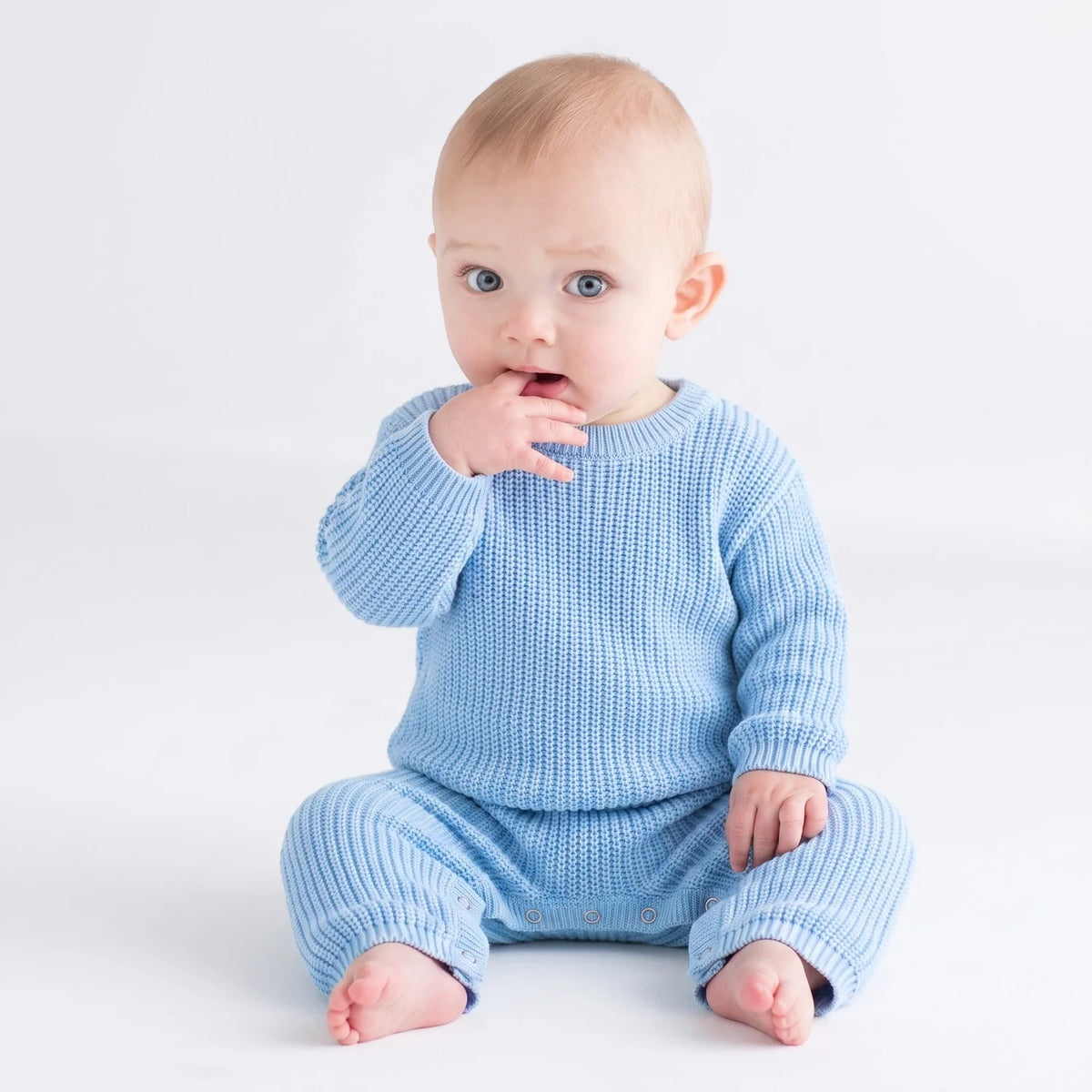 Baby blue knit romper worn by a baby, long sleeves and snap crotch