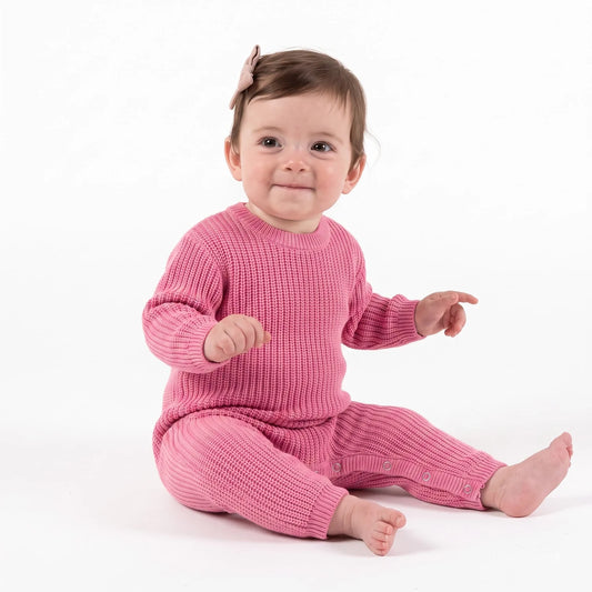 Baby wearing rose pink knit romper with long sleeves and snap leg openings