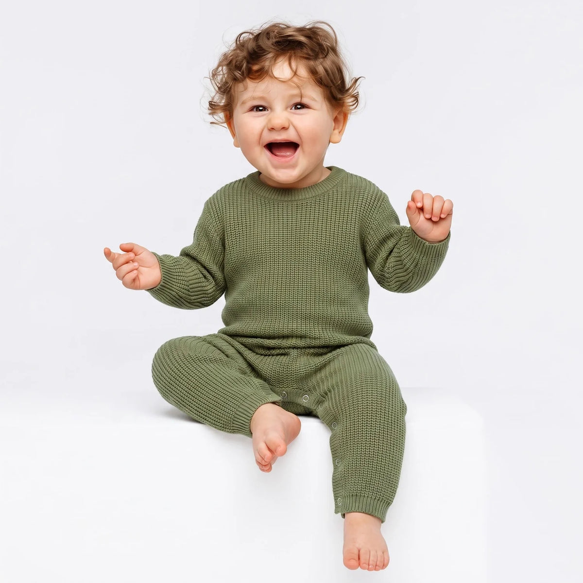Sage green baby knit romper on a seated toddler, long sleeves and snap closure
