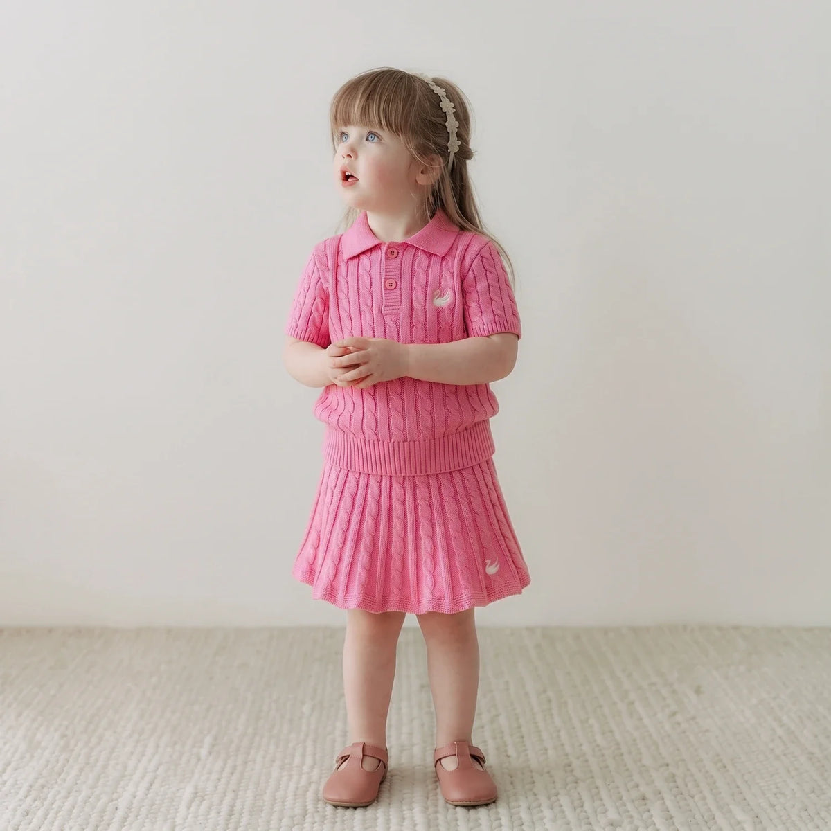 Rose pink cable-knit skirt on a child with ribbed waistband and knit hem