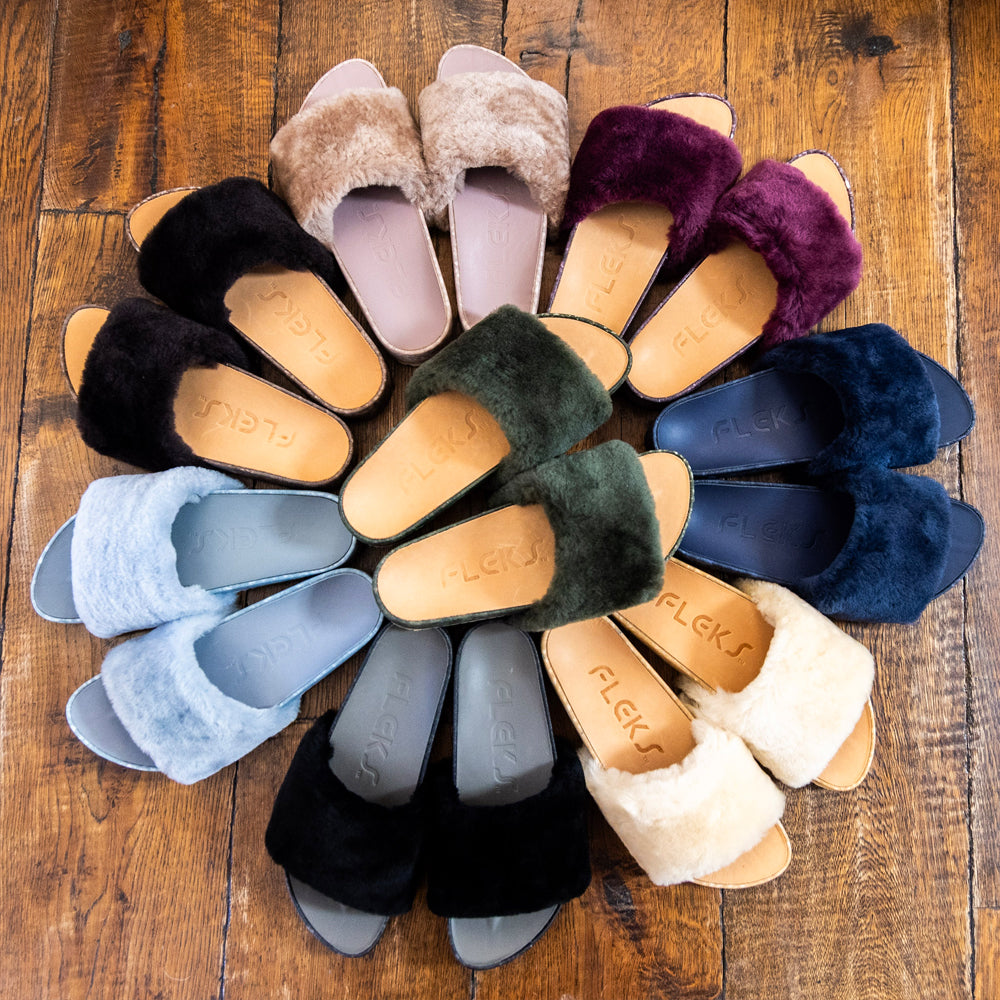 Assorted faux-fur slide sandals in multiple colors on wooden display