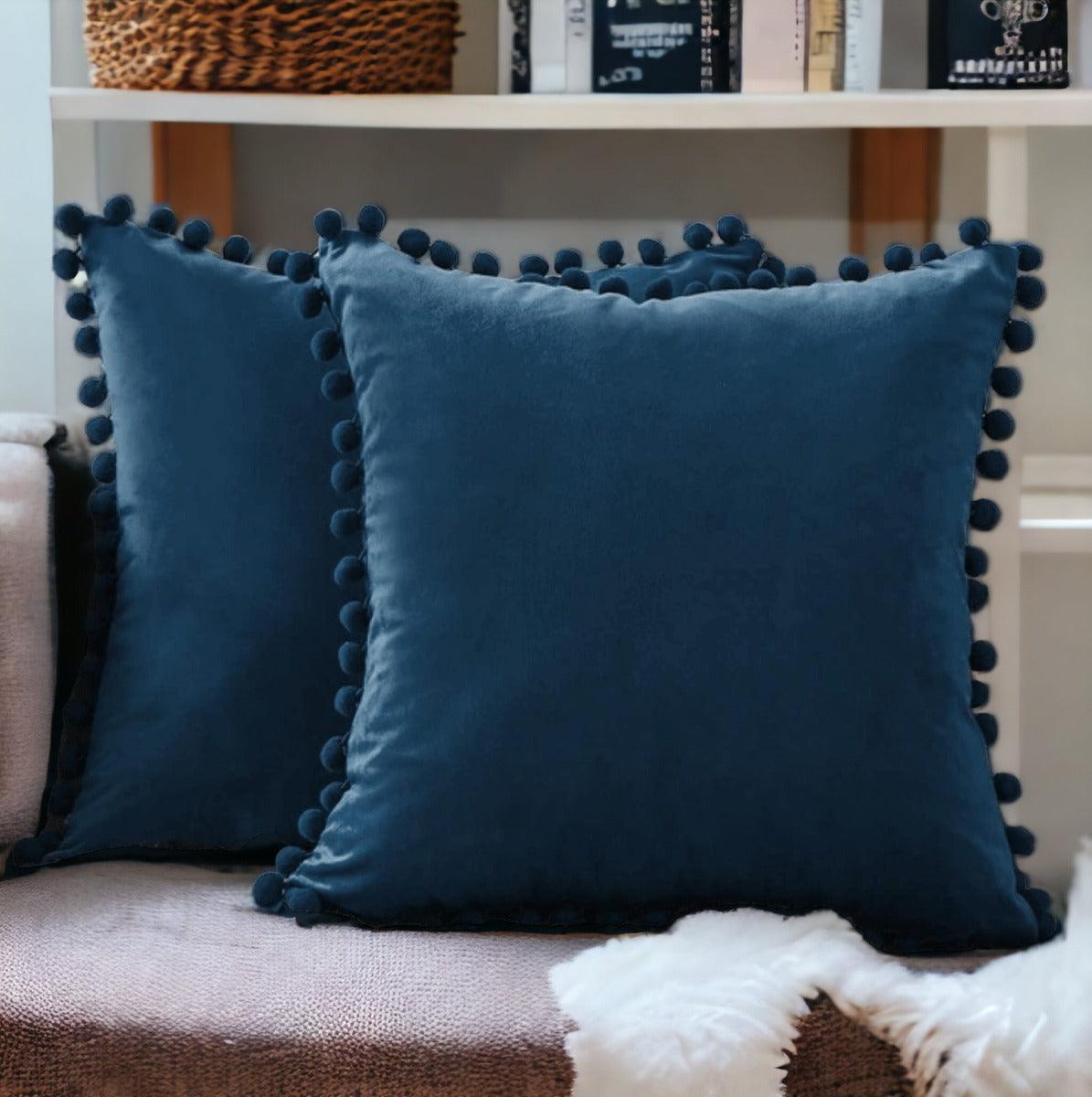 Blue plush throw pillow with pom-pom trim around the edges