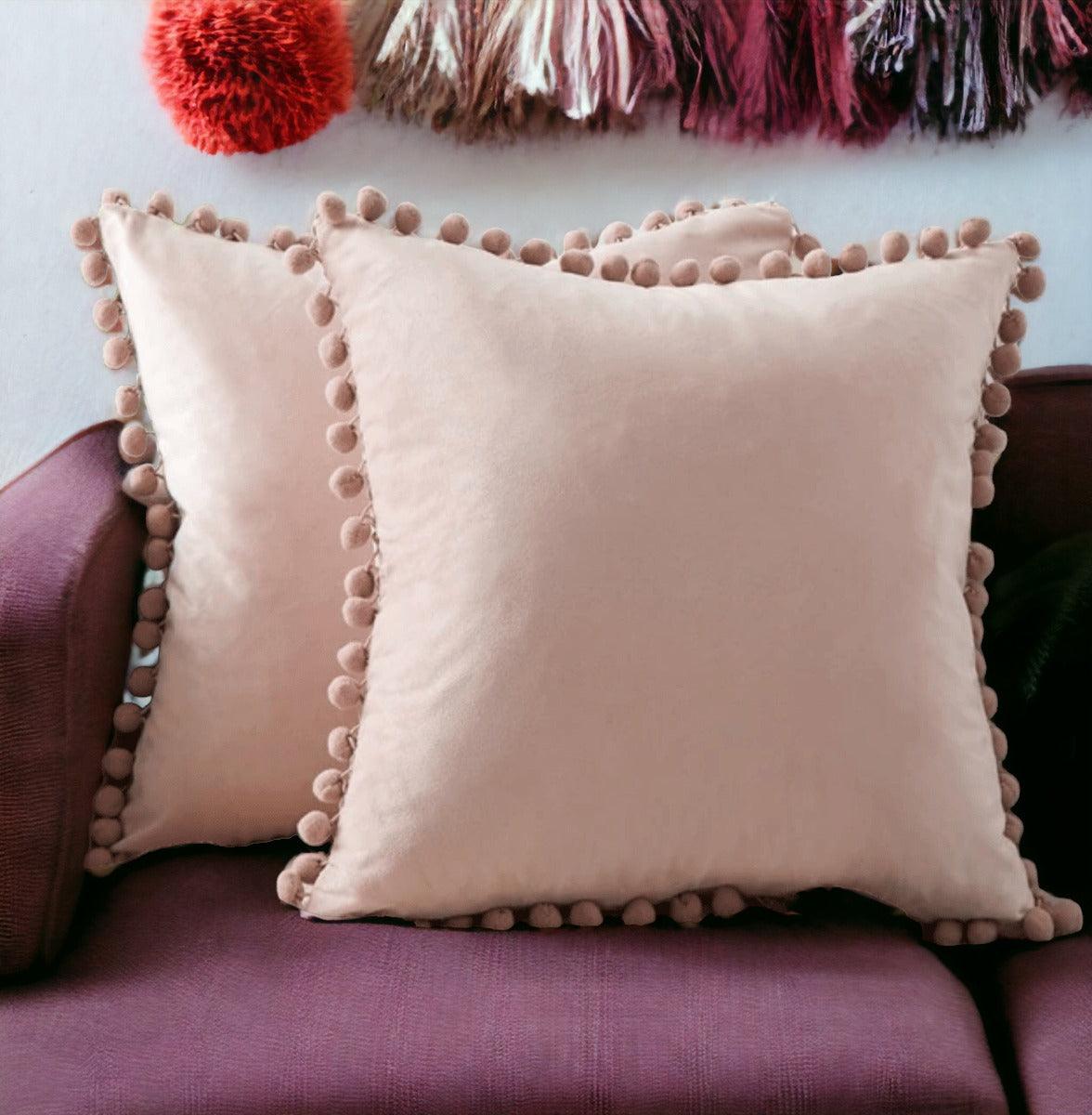 Light pink plush throw pillow with pom-pom trim along the corners and edges