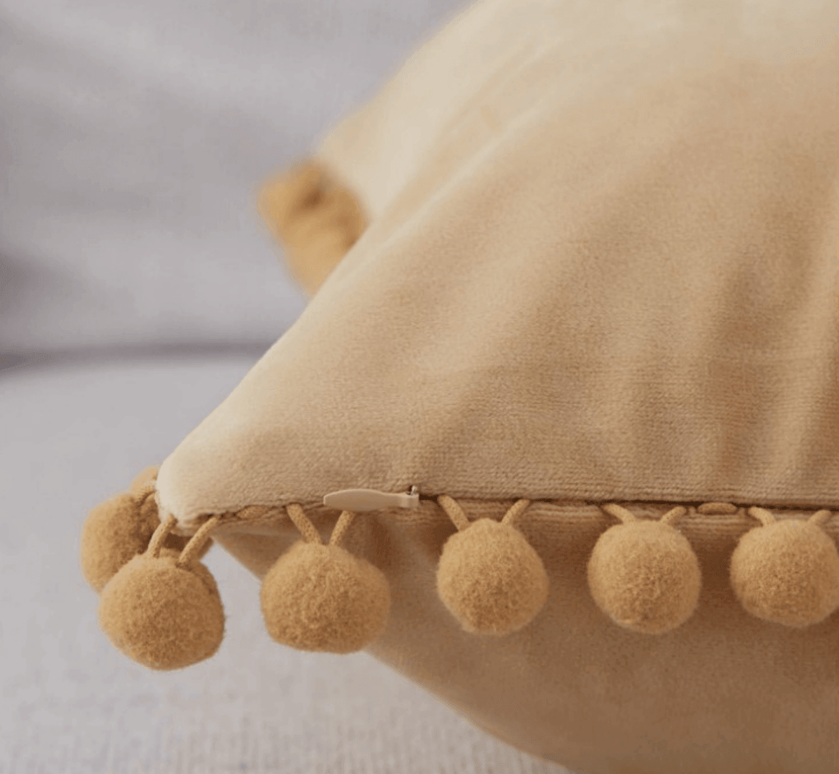 Beige plush pillow edge with pom-pom trim detail