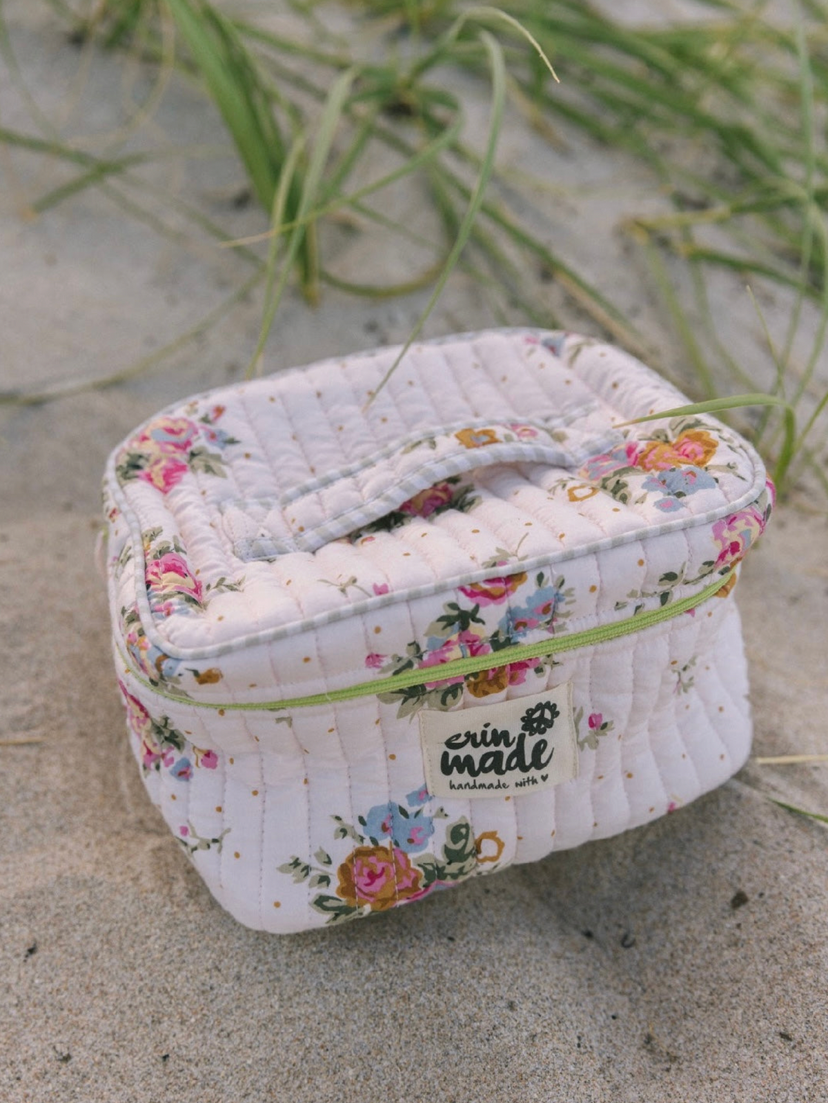 Compact floral quilted travel case with lime zipper, shown closed with top handle
